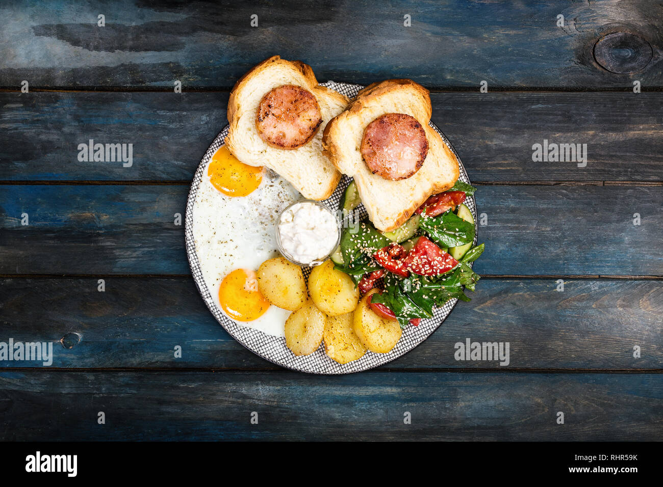 Grande colazione deliziosa con uova fritte, patatine fritte, insalate fresche, prosciutto di pollo su pane e salsa alla panna. Vista dall'alto. Foto Stock