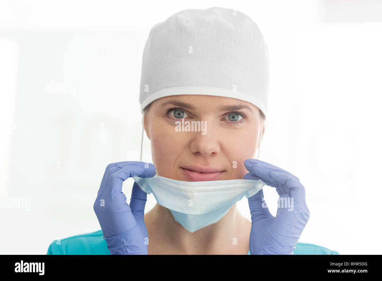 Closeup ritratto di medico sorridente indossando il cappuccio chirurgica la rimozione della maschera in cliniche Foto Stock