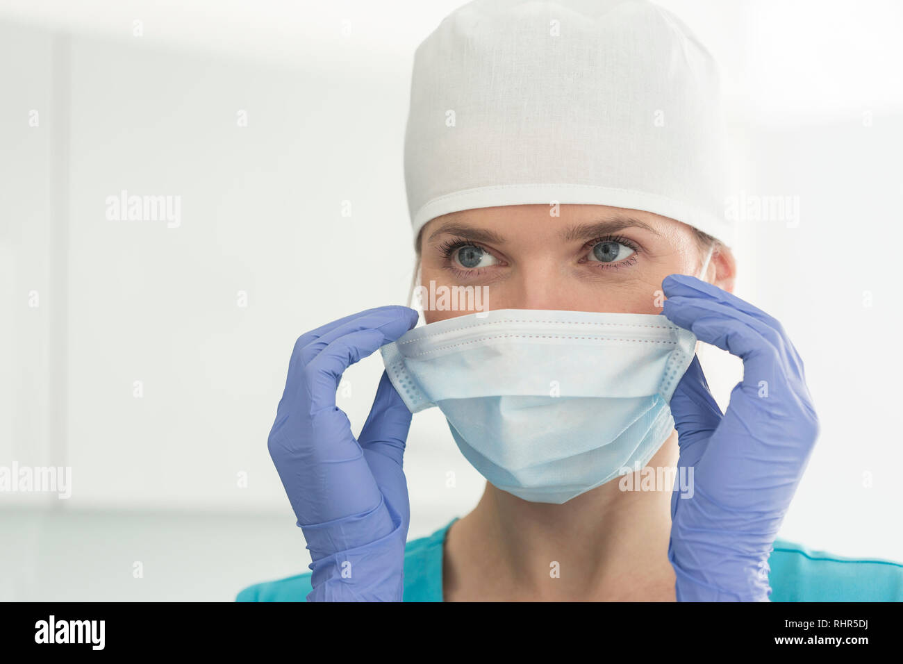 Vista dettagliata del medico donna che indossa il cappuccio chirurgico e la maschera alla clinica Foto Stock