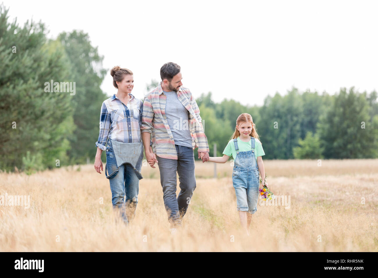 Famiglia camminando sul campo erboso contro sky presso l'azienda Foto Stock