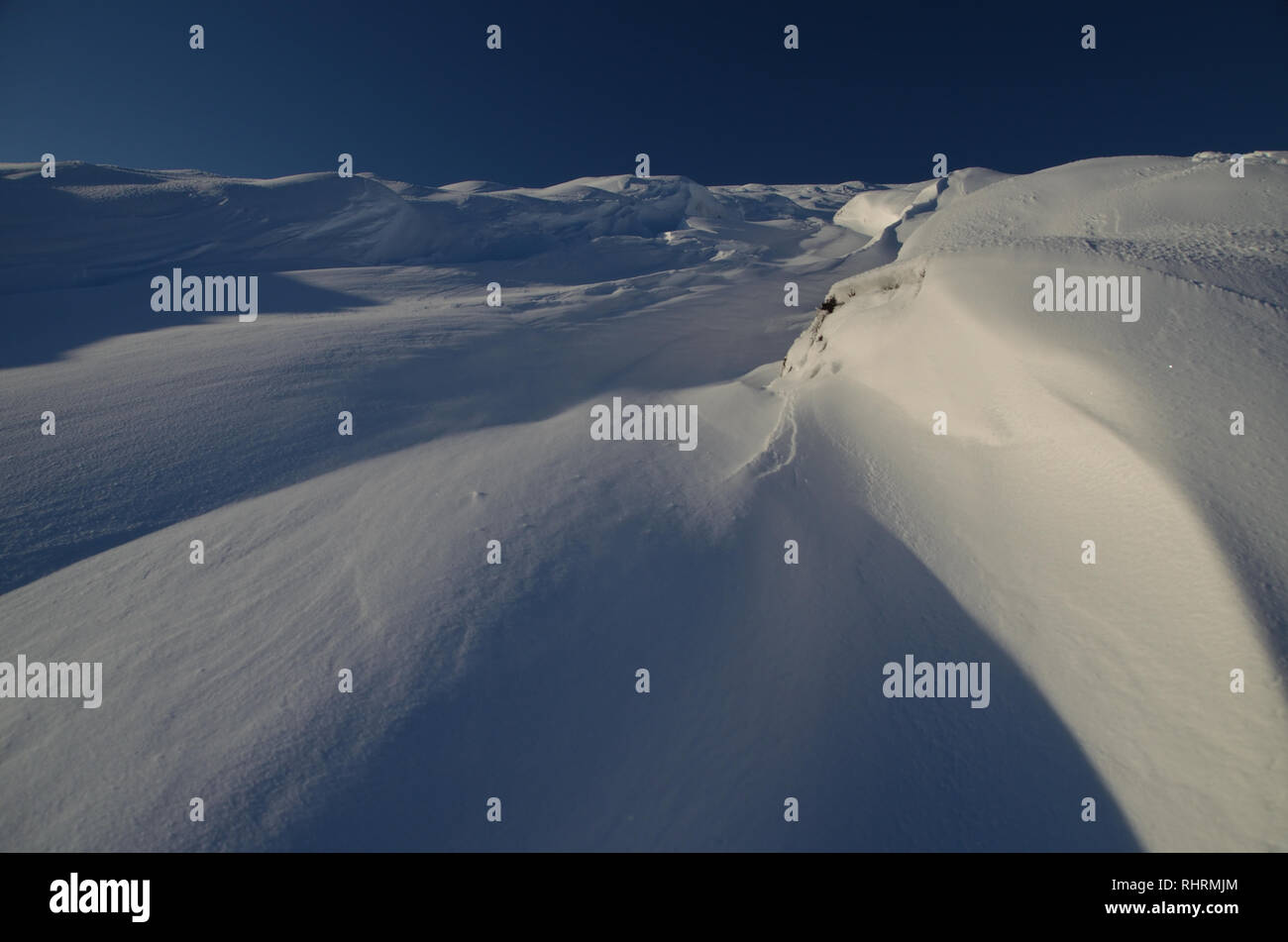 Vento derive soffiata e modelli nella neve sul lato della collina Beinn Tharsuinn, nelle Highlands scozzesi, Gran Bretagna Foto Stock