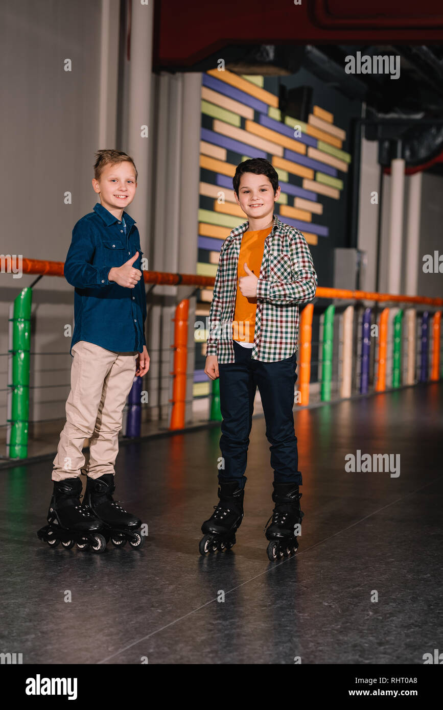 Preteen boys in pattini a rotelle in posa con il pollice in alto Foto Stock