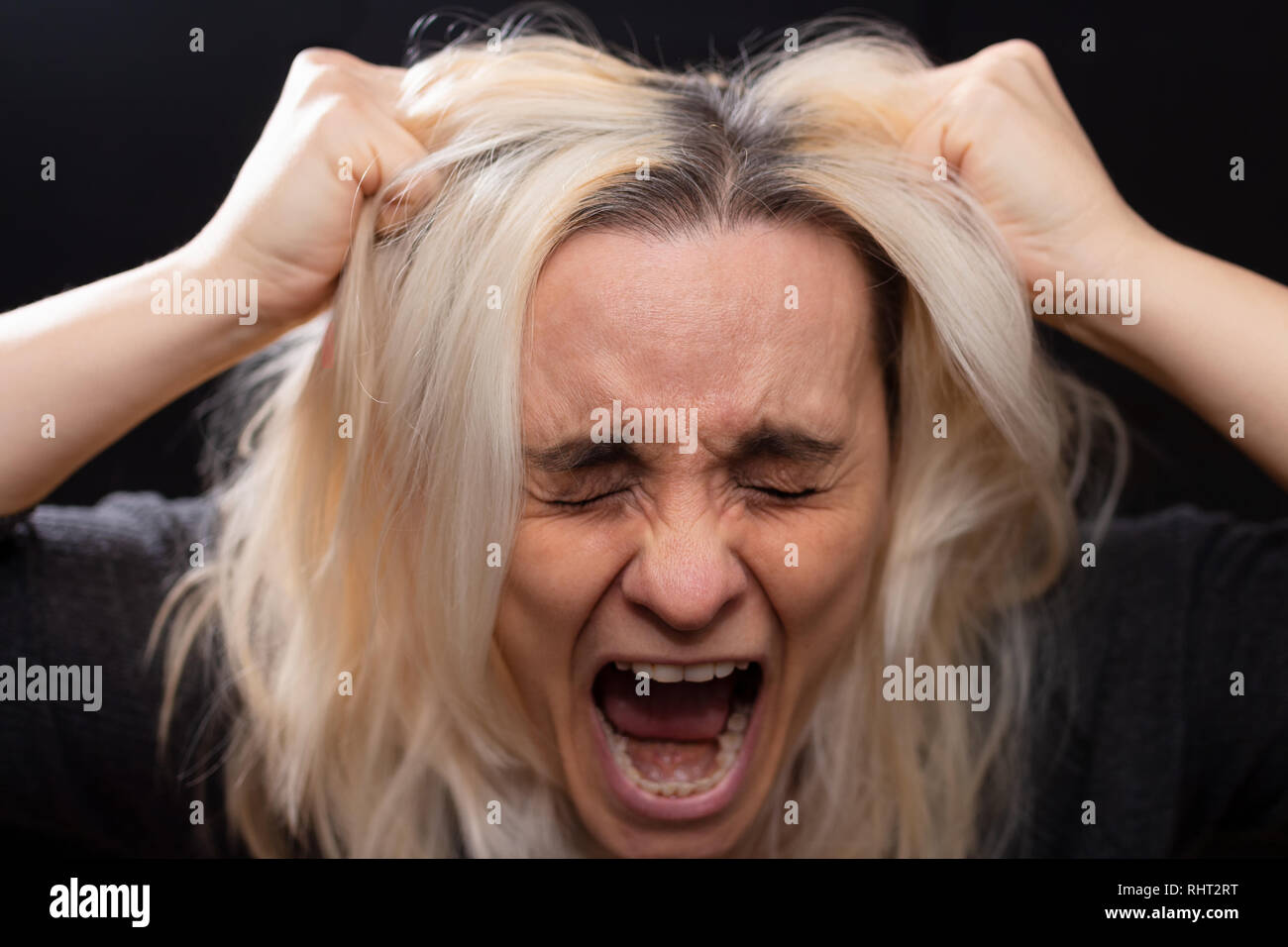 Donna bionda urlando e tirando i capelli con le mani Foto Stock