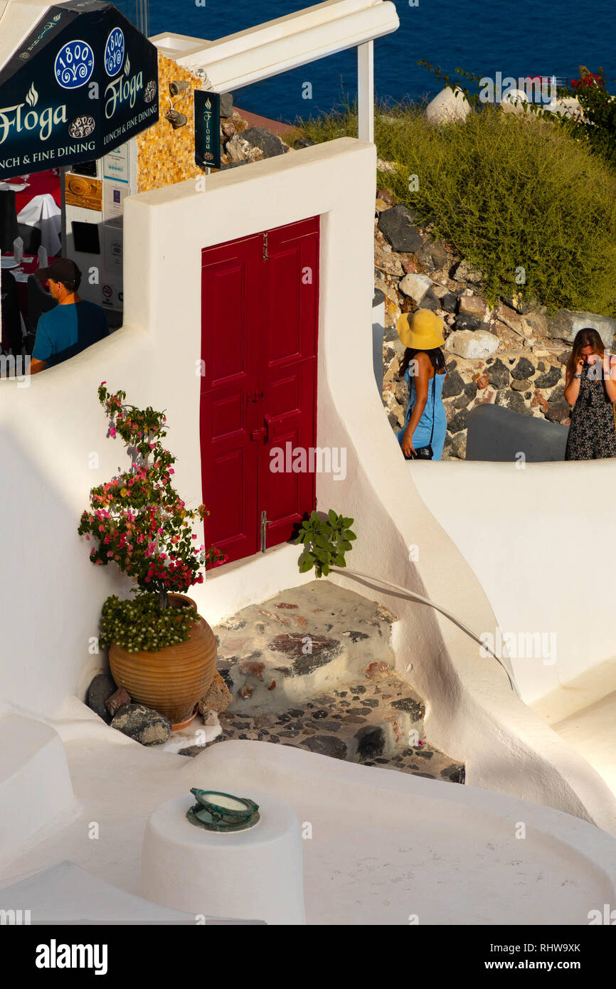 Tortuose strade e scale di Santorini. Donne salendo al piano superiore. Porta Rossa che conduce alle scale. Foto Stock