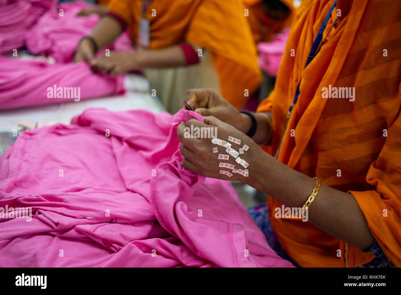 Vesti i lavoratori sono visti lavorare in un profilato di finitura. Gli indumenti industria in Bangladesh guidare la crescita economia e ora è la principale fonte di responsabilizzare le donne operaie nel paese. Donne provenienti da diverse parti del Bangladesh venire in città per lavoro indumenti in settori in cui esse vengono pagati circa 95 USD per mese. Foto Stock