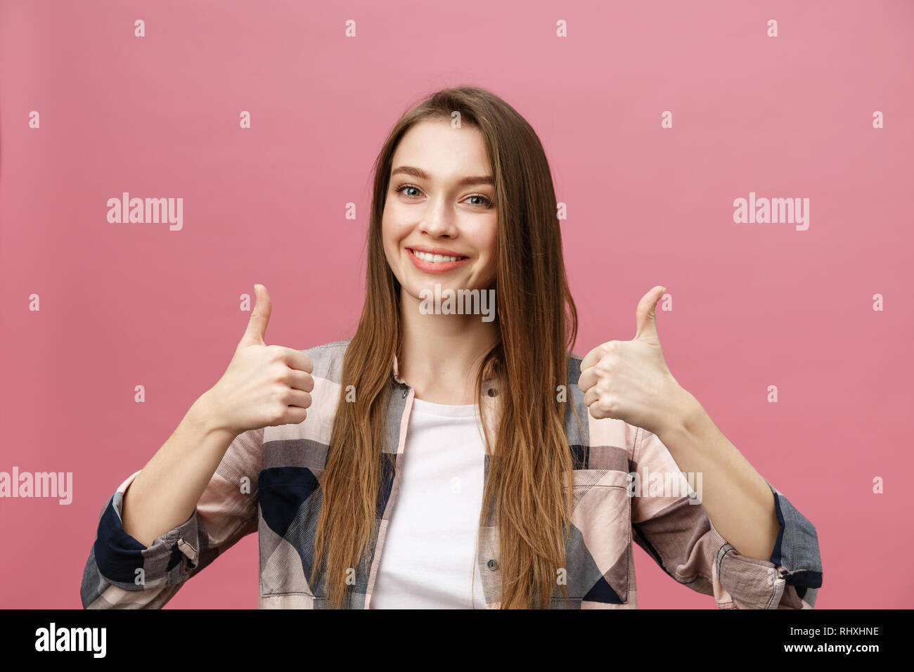 Close-up shot di sorridente ragazza piuttosto che mostra il pollice fino gesto. Femmina isolato su sfondo rosa in studio. Foto Stock