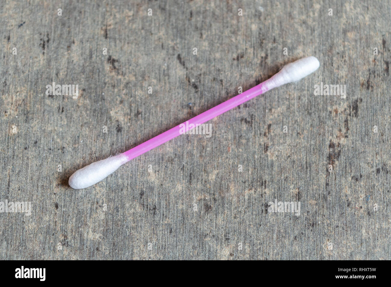 Un bastoncino di cotone utilizzati per la pulizia di orecchie mantenuta su una trama Tabella grigia Foto Stock