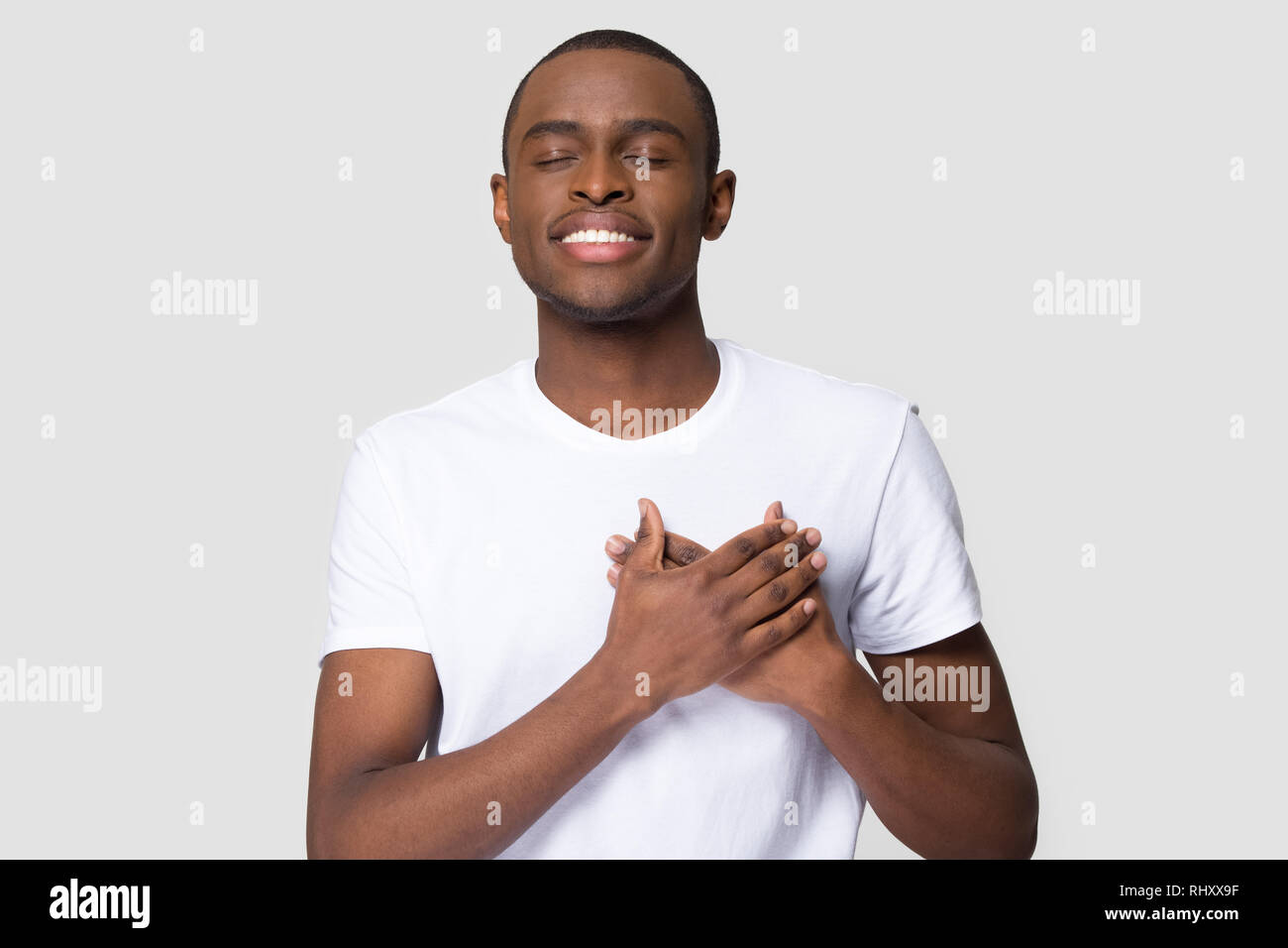 Grato felice l'uomo africano tenendo le mani sul petto sentimento di apprezzamento Foto Stock