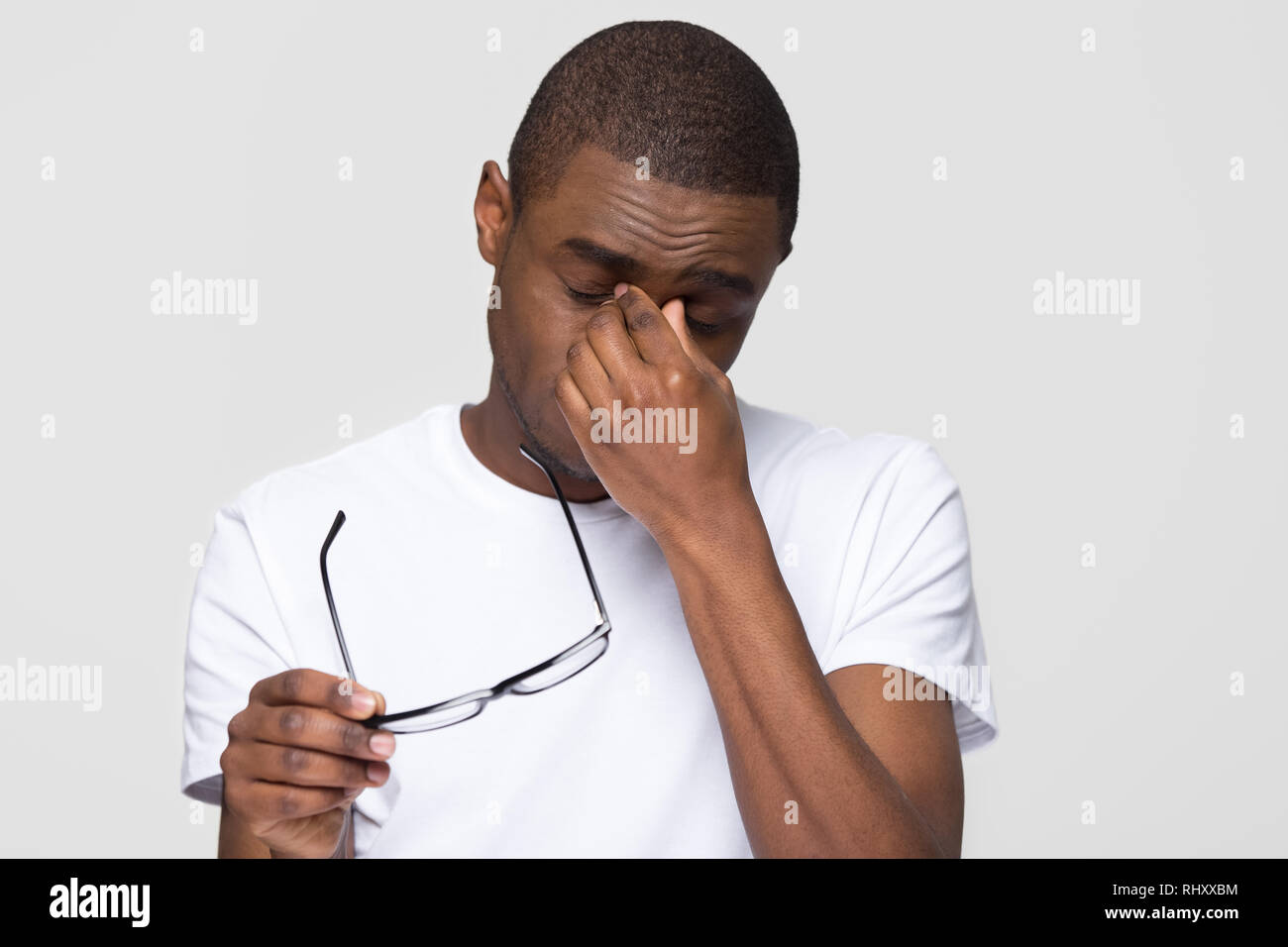 Stanco African American uomo naso massaggiante ponte prendendo gli occhiali off Foto Stock