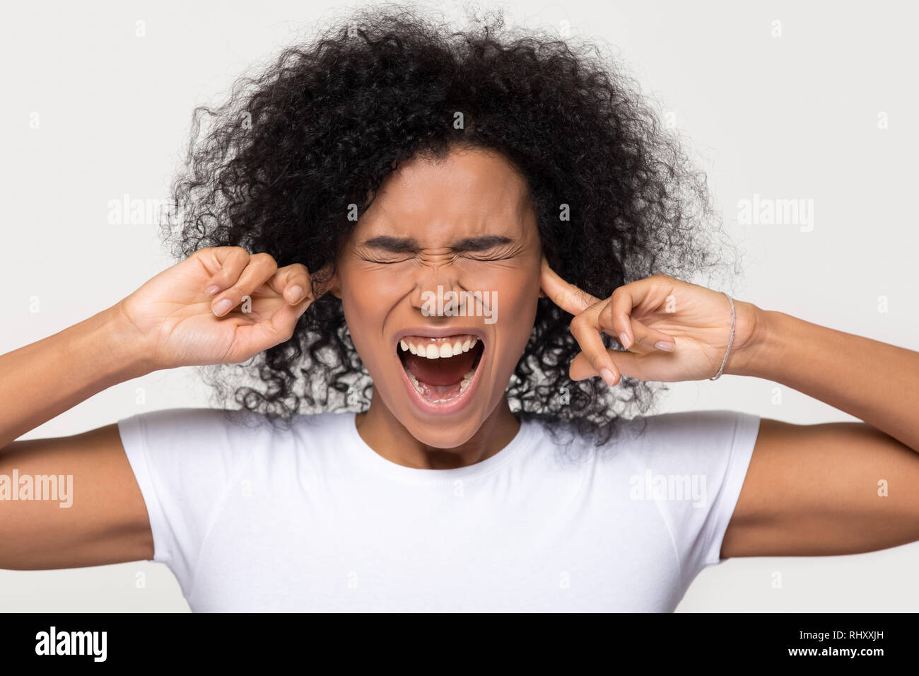 Testardo arrabbiato nero donna sticking plug dita nelle orecchie Foto Stock