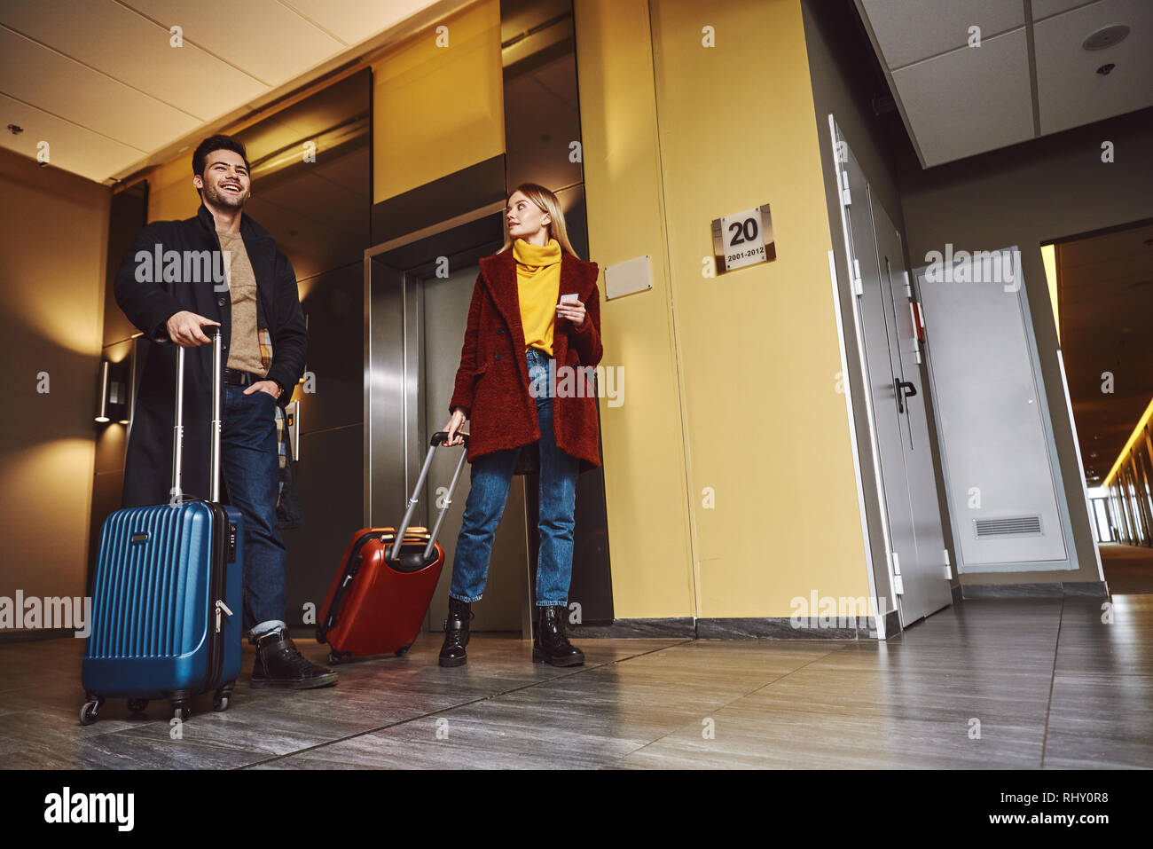 Infine la destinazione. Coppia giovane entra al pavimento dell'hotel con i loro bagagli e avente una chat Foto Stock