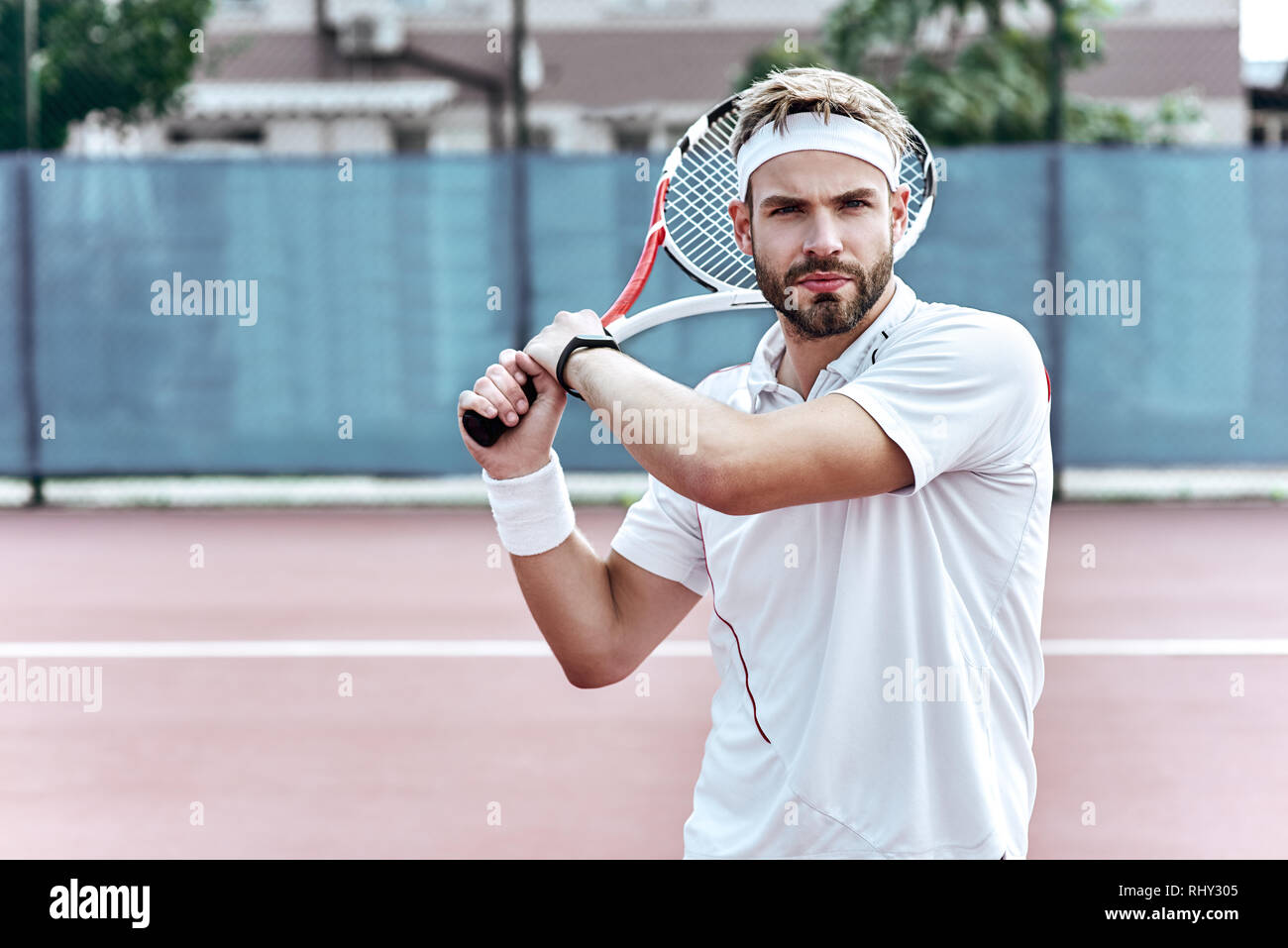 Uomo bello in bianco per abbigliamento sportivo con il racket nelle sue mani è completamente concentrata sul gioco Foto Stock
