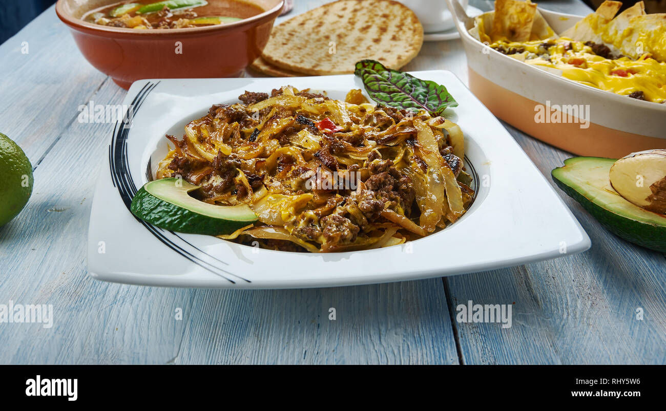 Tex Mex cavolo padella Carni bovine oppato con messicano piccante miscela di formaggio, cucina tex-mex e tradizionali piatti assortiti, vista dall'alto. Foto Stock