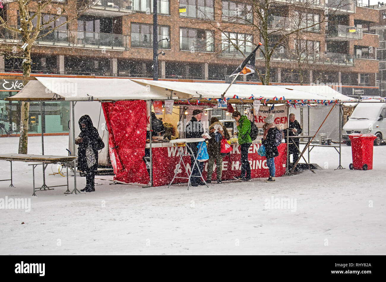 Rotterdam, Paesi Bassi, 22 Gennaio 2019: la vita va avanti durante una tempesta di neve a una pressione di stallo di pesce sul mercato martedì sulla piazza Binnenrotte Foto Stock