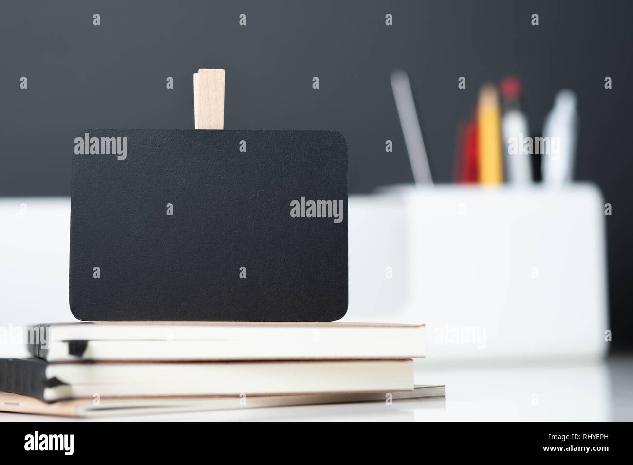 Close up lavagna clip su notebook con blur moderno casella matita su tavola e grigio scuro muro in office desk,mock up lo spazio per la visualizzazione di progettazione o di te Foto Stock