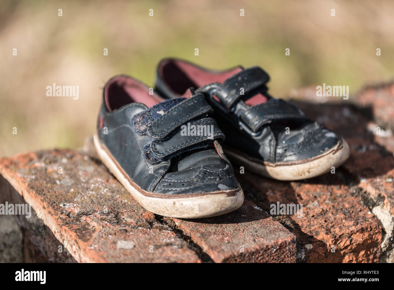 Una coppia di Lost, abbandonato kid scarpe possono simbolo manca qualche bambino, un paio di scarpe di capretto su un muro di mattoni Foto Stock