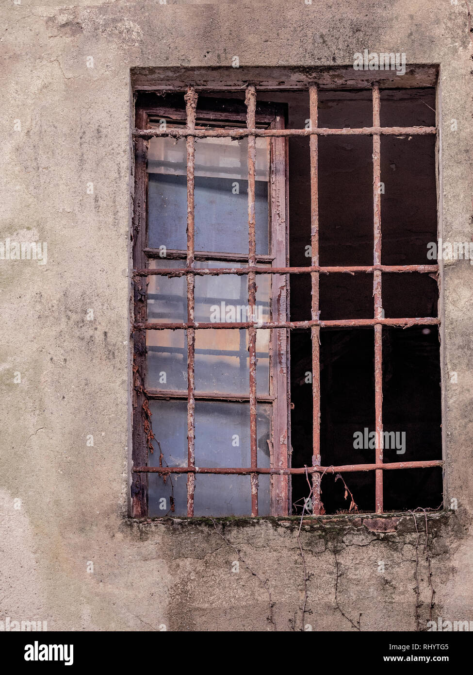 Finestra di un vecchio edificio disabitato con barre arrugginito Foto Stock