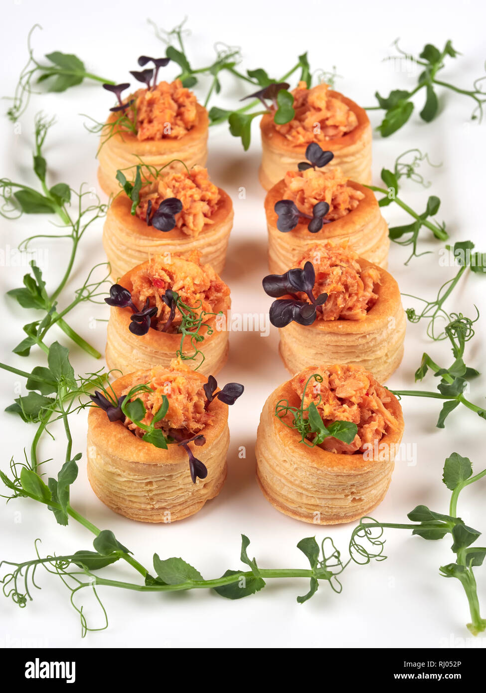 Sfogliatine con un piccante, chunky riempimento salmone, guarnita con germogli di piselli Foto Stock
