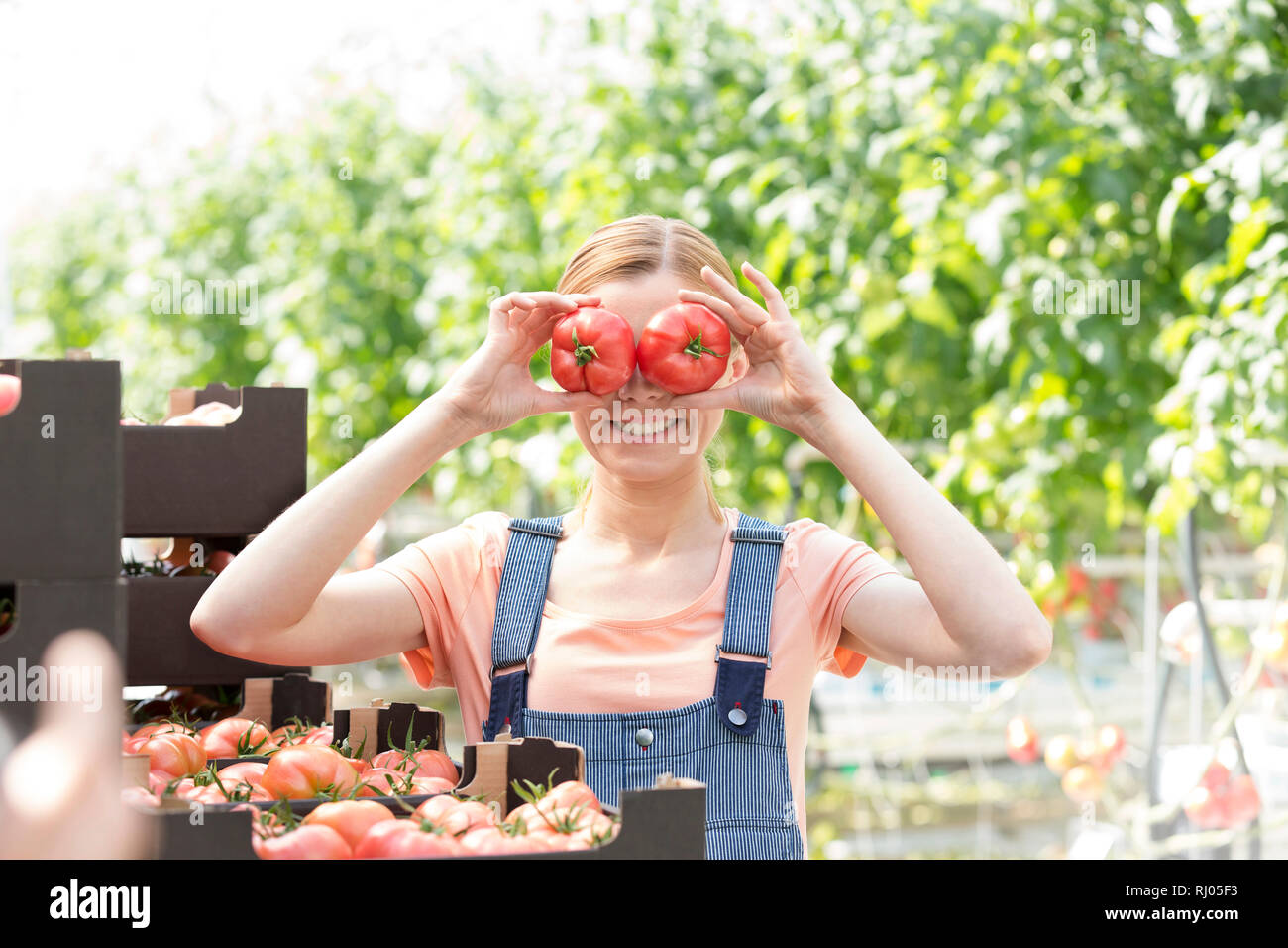 Donna sorridente giocando con i pomodori durante il riposo in fattoria Foto Stock