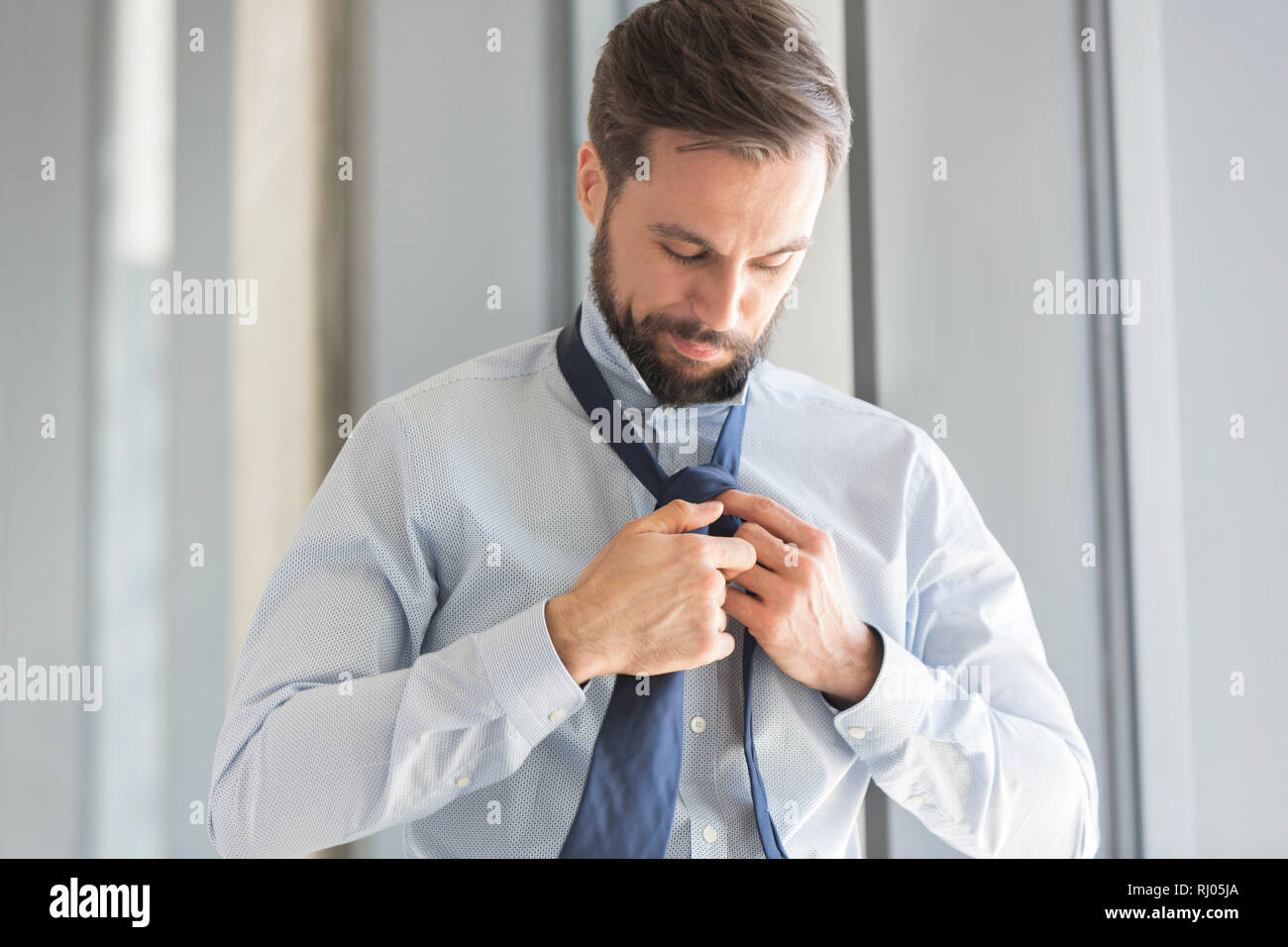 Giovane imprenditore che indossa cravatta in ufficio Foto Stock
