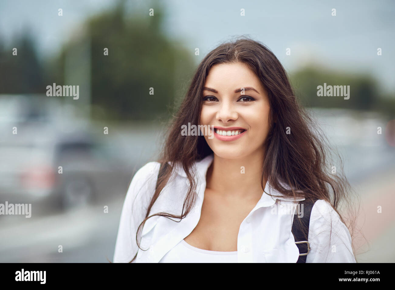 Bella bruna in piedi all'aperto e sorridente Foto Stock