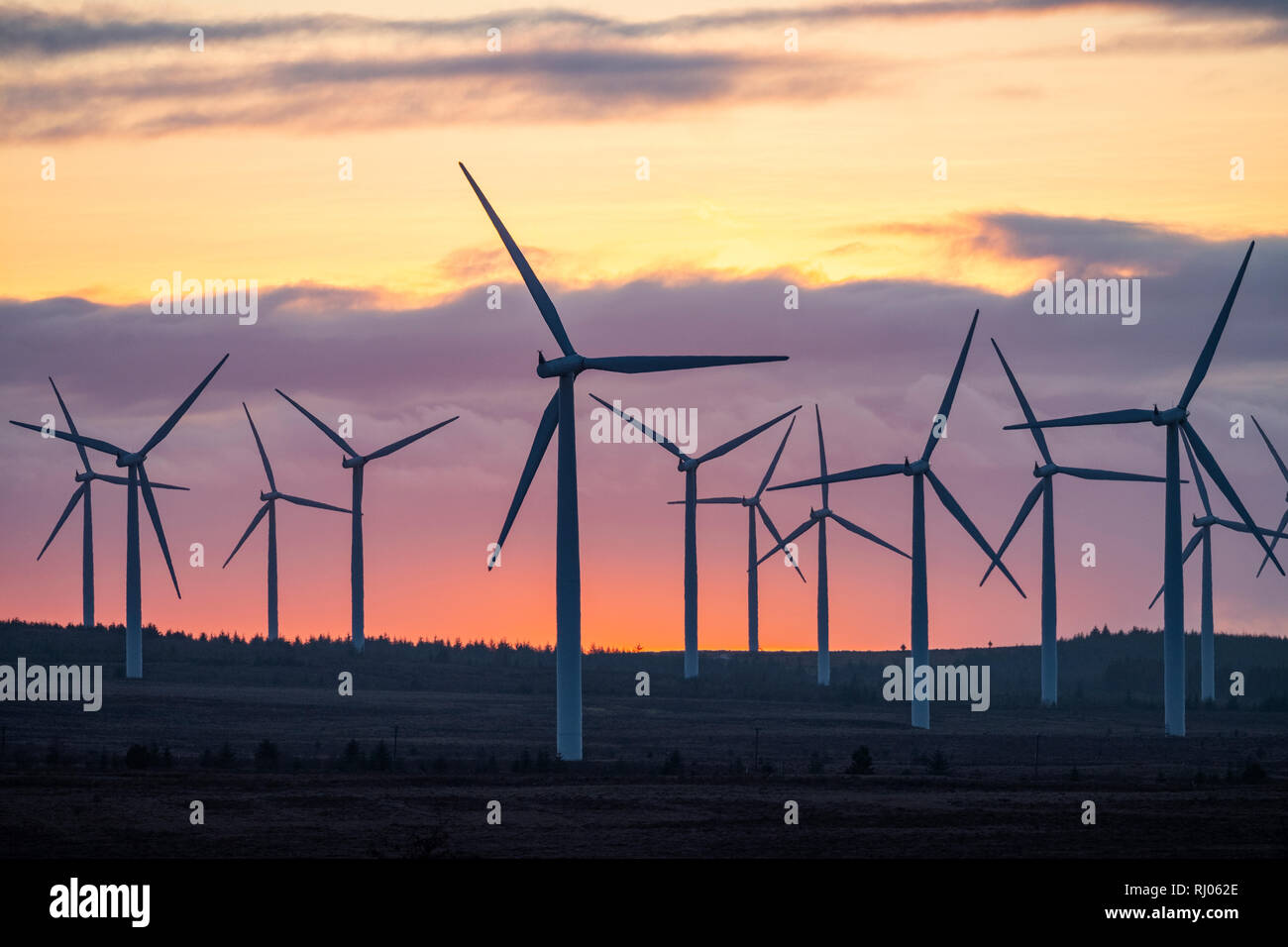 Il sole tramonta dietro il diritto nero wind farm vicino a via, South Lanarkshire, Scozia. Foto Stock