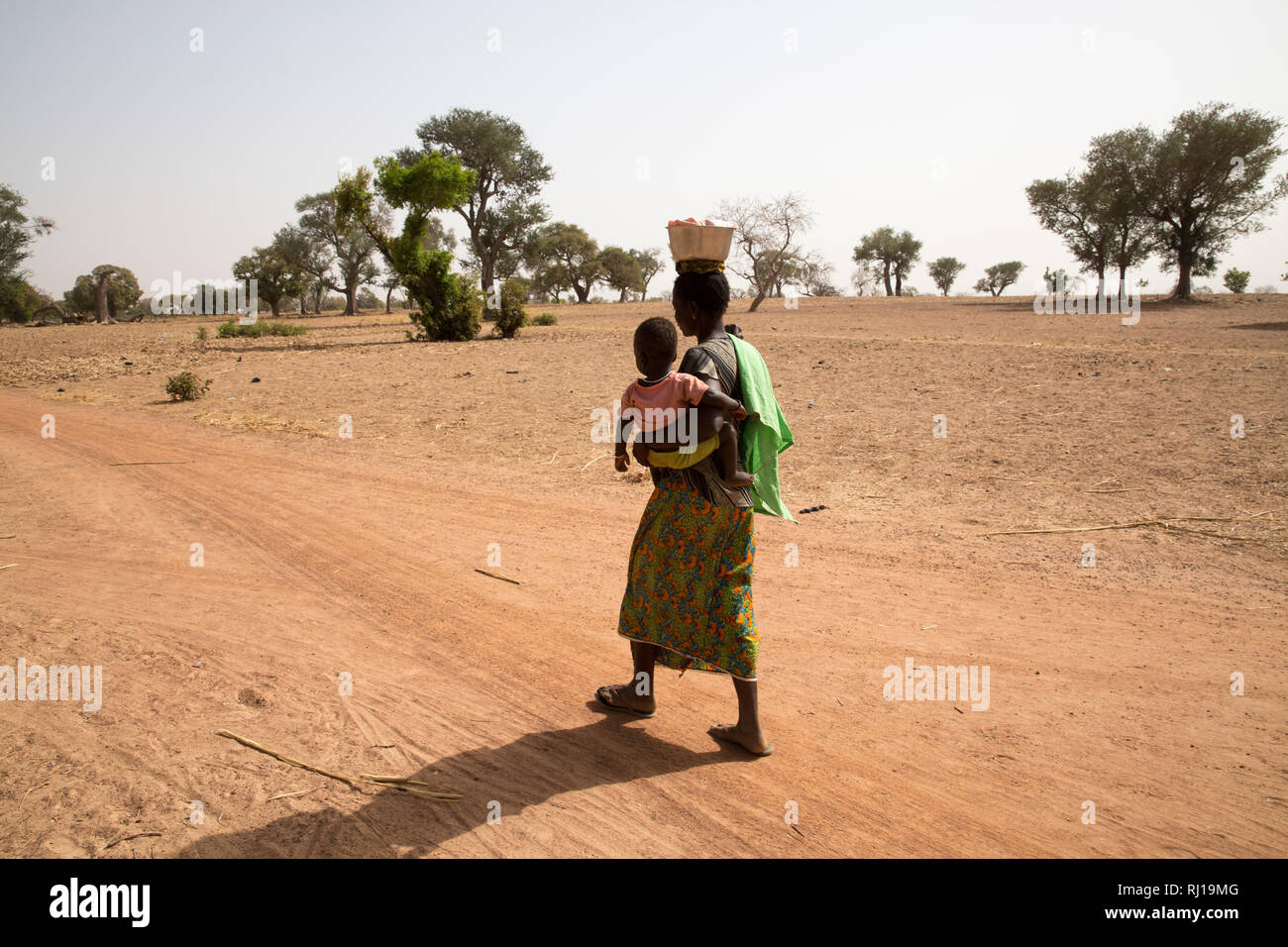 Il villaggio di Samba, Provincia Yako, Burkina Faso; Sally Zoundi, 35, con il suo bambino Salomon Zoundi, quindici mesi, sul suo modo di lavorare presso il locale goldmine per sostenere la sua famiglia. Foto Stock