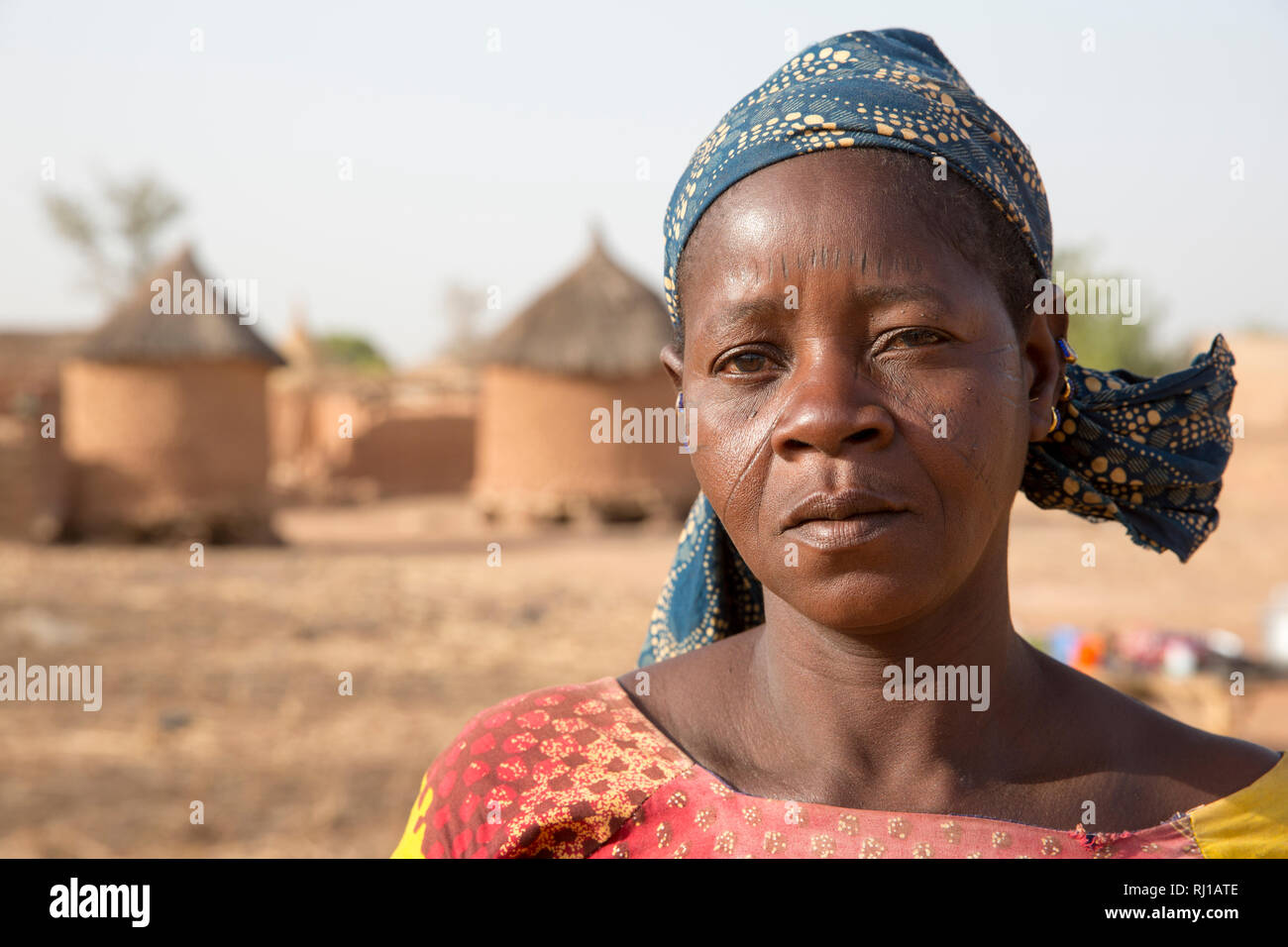 Villaggio Kourono, provincia Yako, Burkina Faso; un ritratto di una donna con marcatura tribali sul suo volto, nella parte anteriore del villaggio di negozi di granella. Foto Stock