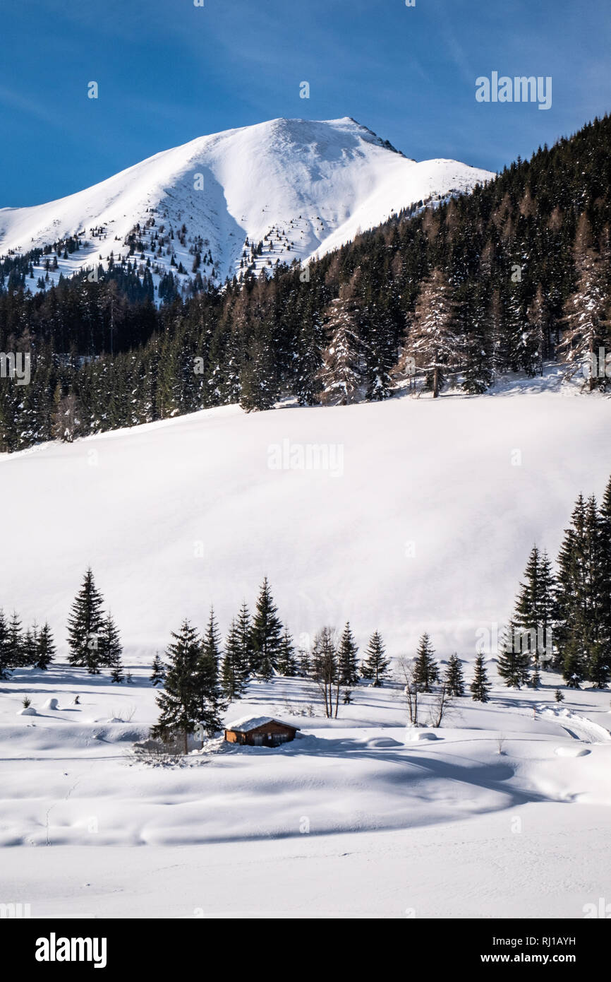 Coperta di neve lago ghiacciato con piccola capanna casa di vacanza-resort Hohentauern su una soleggiata giornata invernale in Stiria, Austria Foto Stock