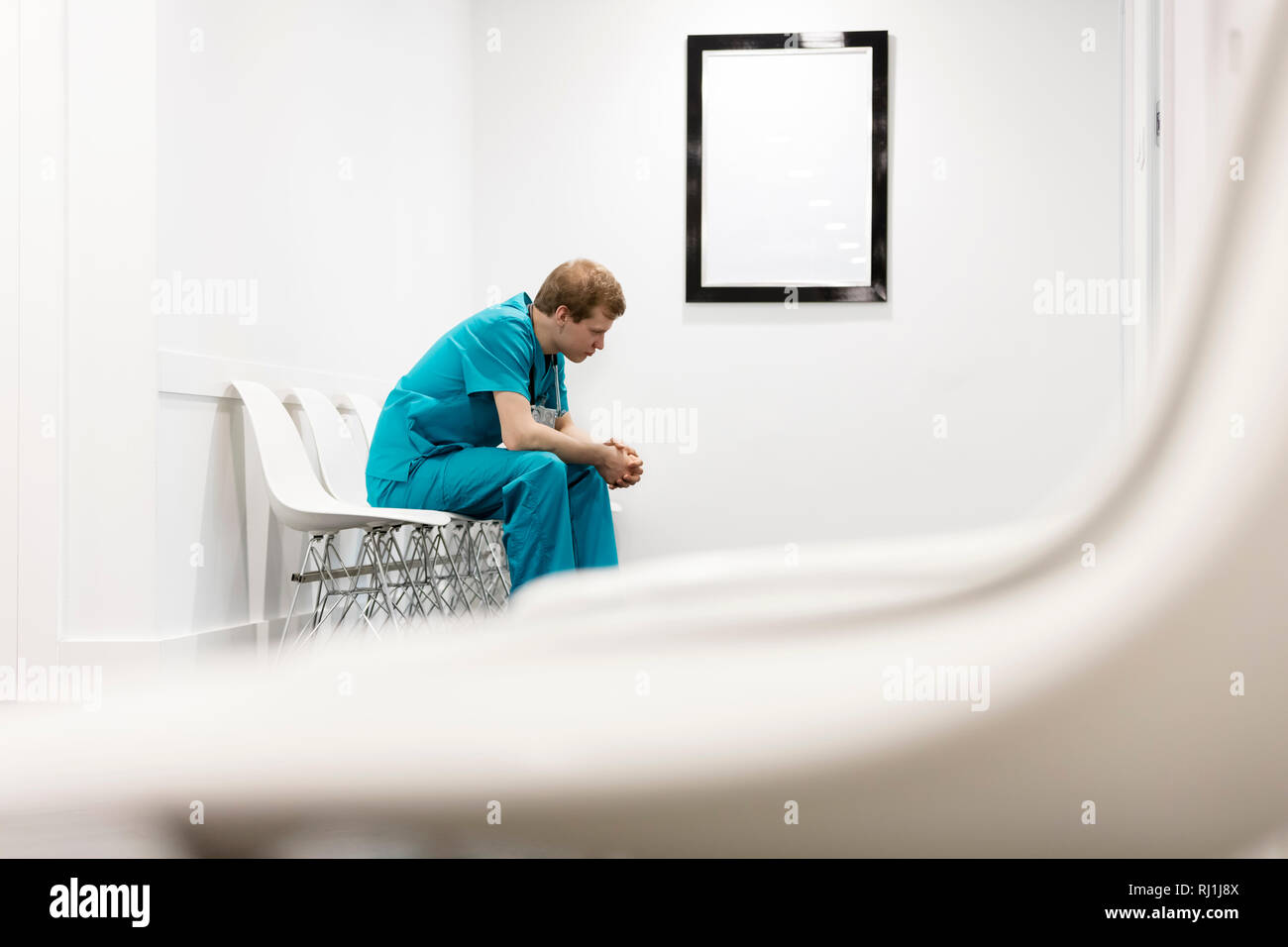 Considerato l'infermiera in uniforme seduto su una sedia al corridoio dell'ospedale Foto Stock