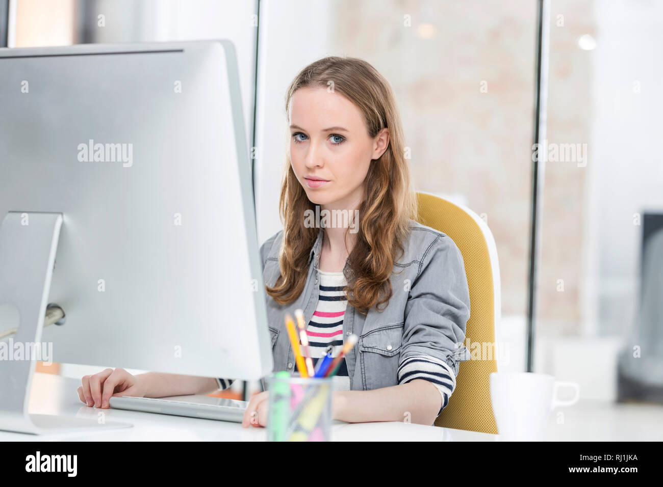 Ritratto di creative imprenditrice utilizzando computer desktop in ufficio Foto Stock