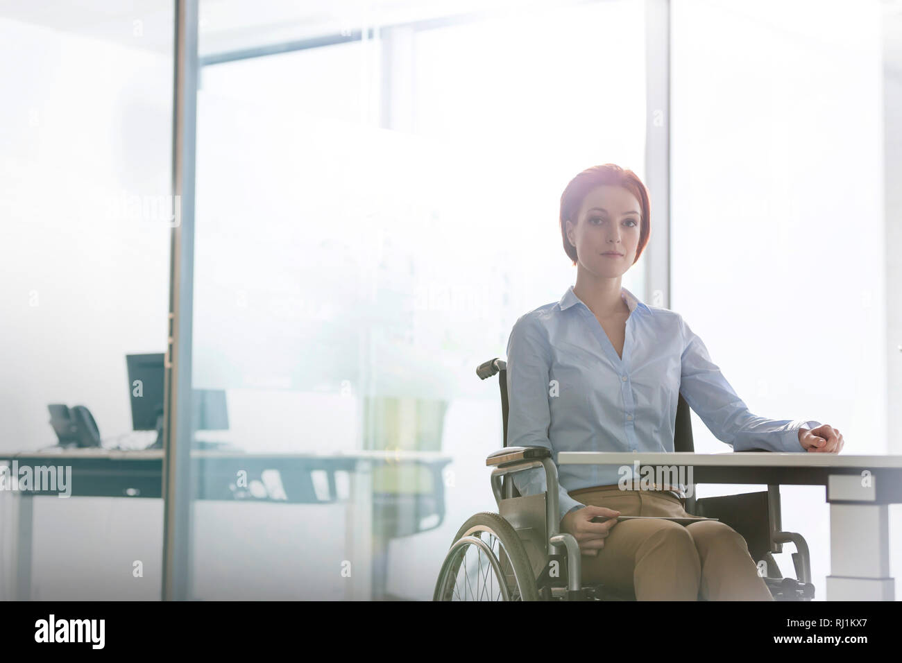 Ritratto di certi disabili imprenditrice seduto alla scrivania in ufficio Foto Stock