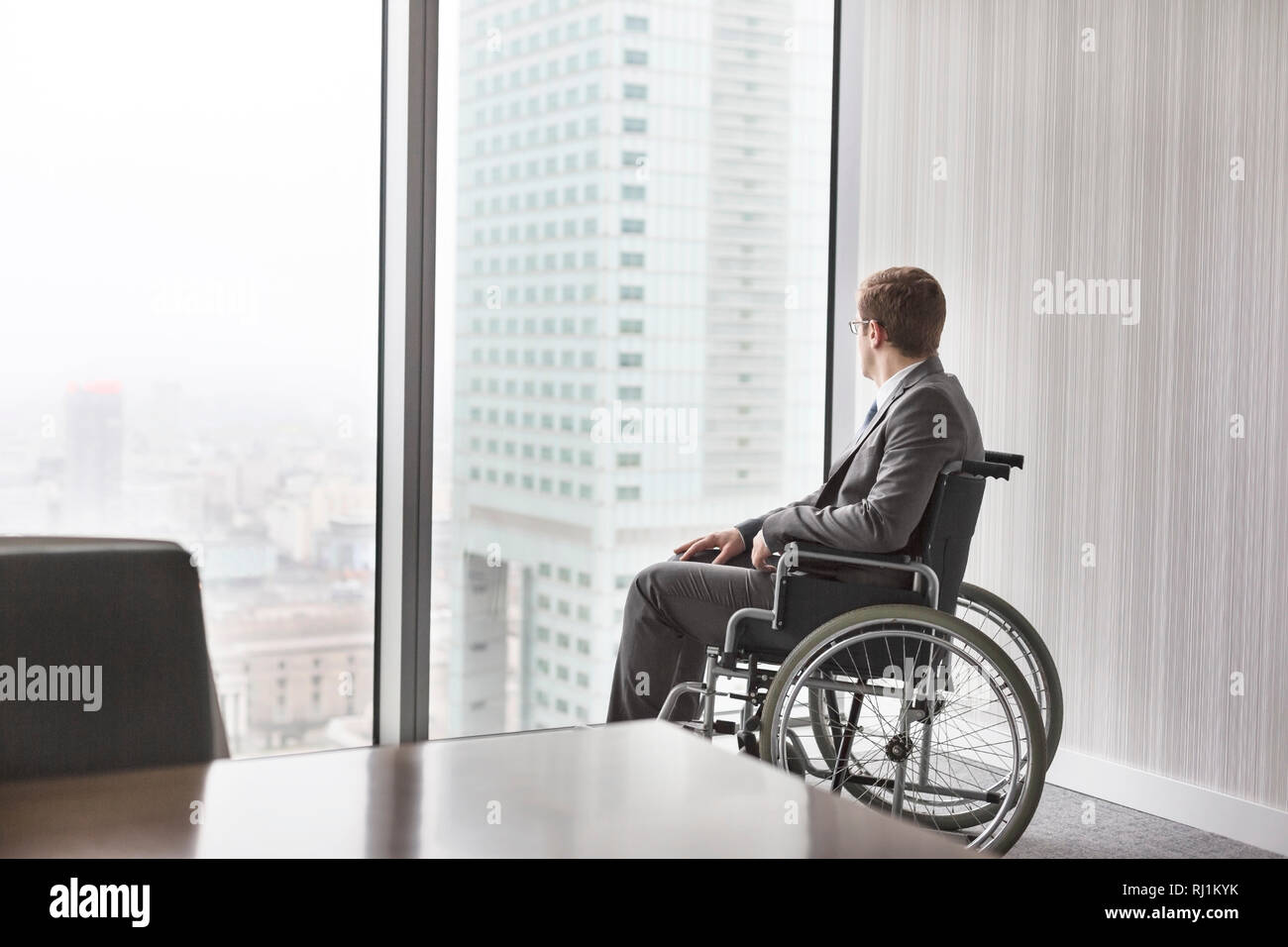 Considerato imprenditore disabili guardando attraverso la finestrella in sala riunioni presso un ufficio moderno Foto Stock