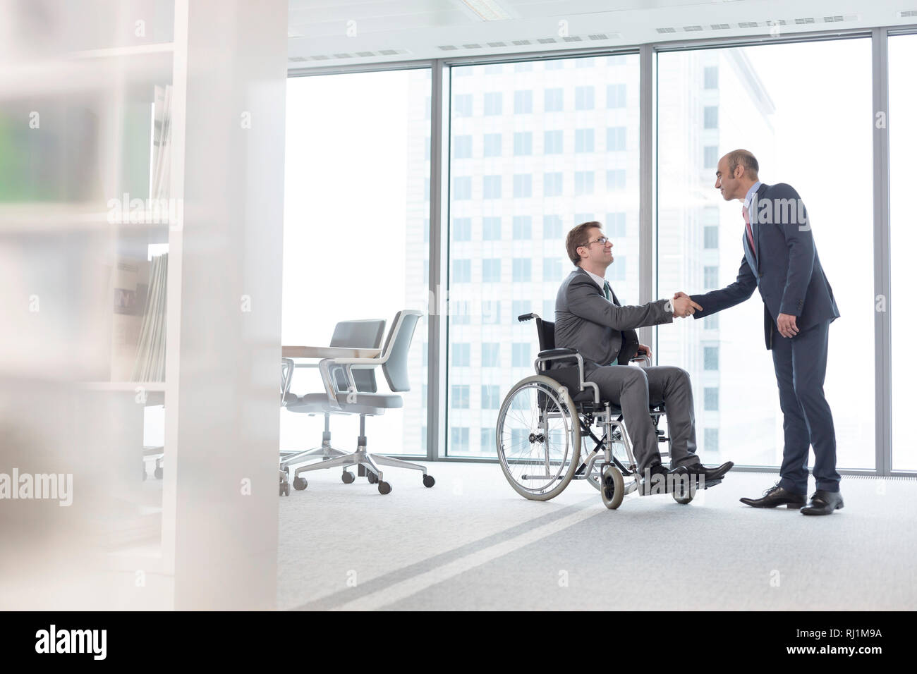 Imprenditore stringono le mani con sorridente collega disabili nella sala riunioni in ufficio Foto Stock