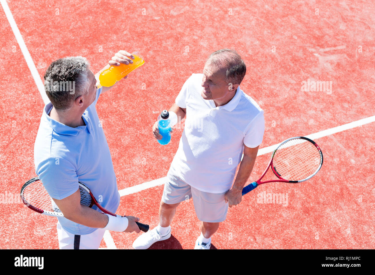 Angolo di alta vista degli uomini di parlare mentre si sta in piedi sul campo da tennis durante il match Foto Stock