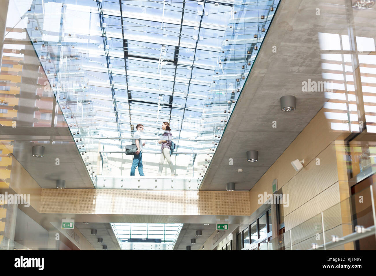 Basso angolo di visione degli studenti a piedi sul pavimento di vetro al campus universitario Foto Stock