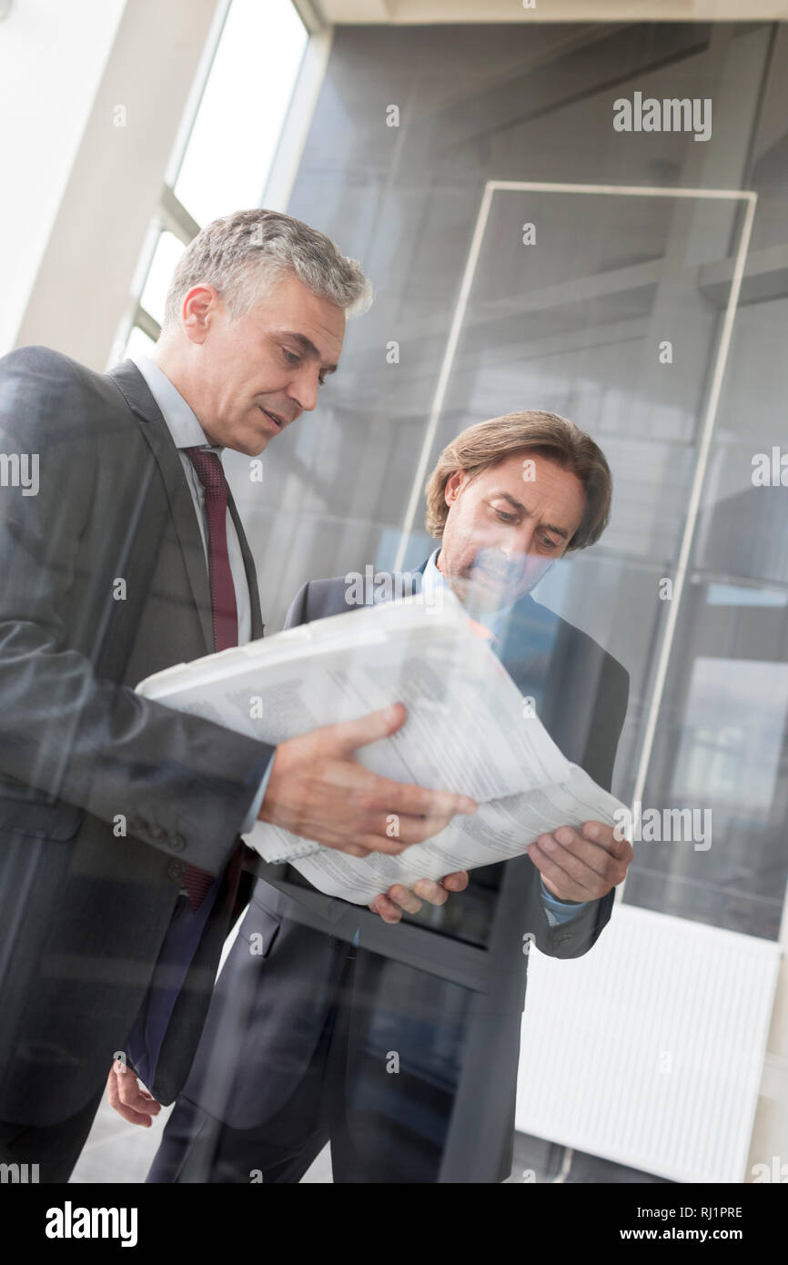 Imprenditori maturi discutendo su documento permanente, mentre nel nuovo ufficio Foto Stock