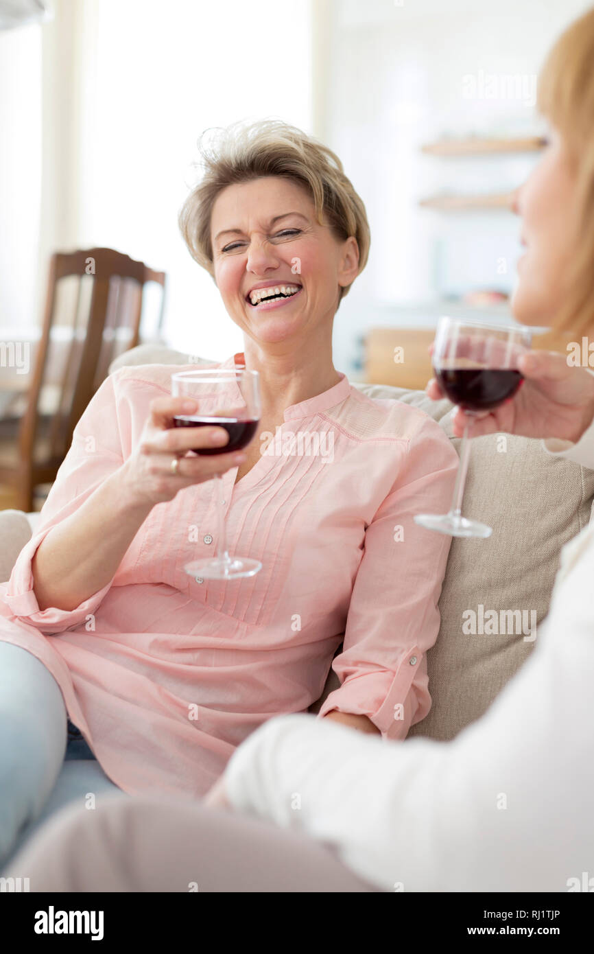 Allegro coppia amici con drink seduti sul divano di casa Foto Stock