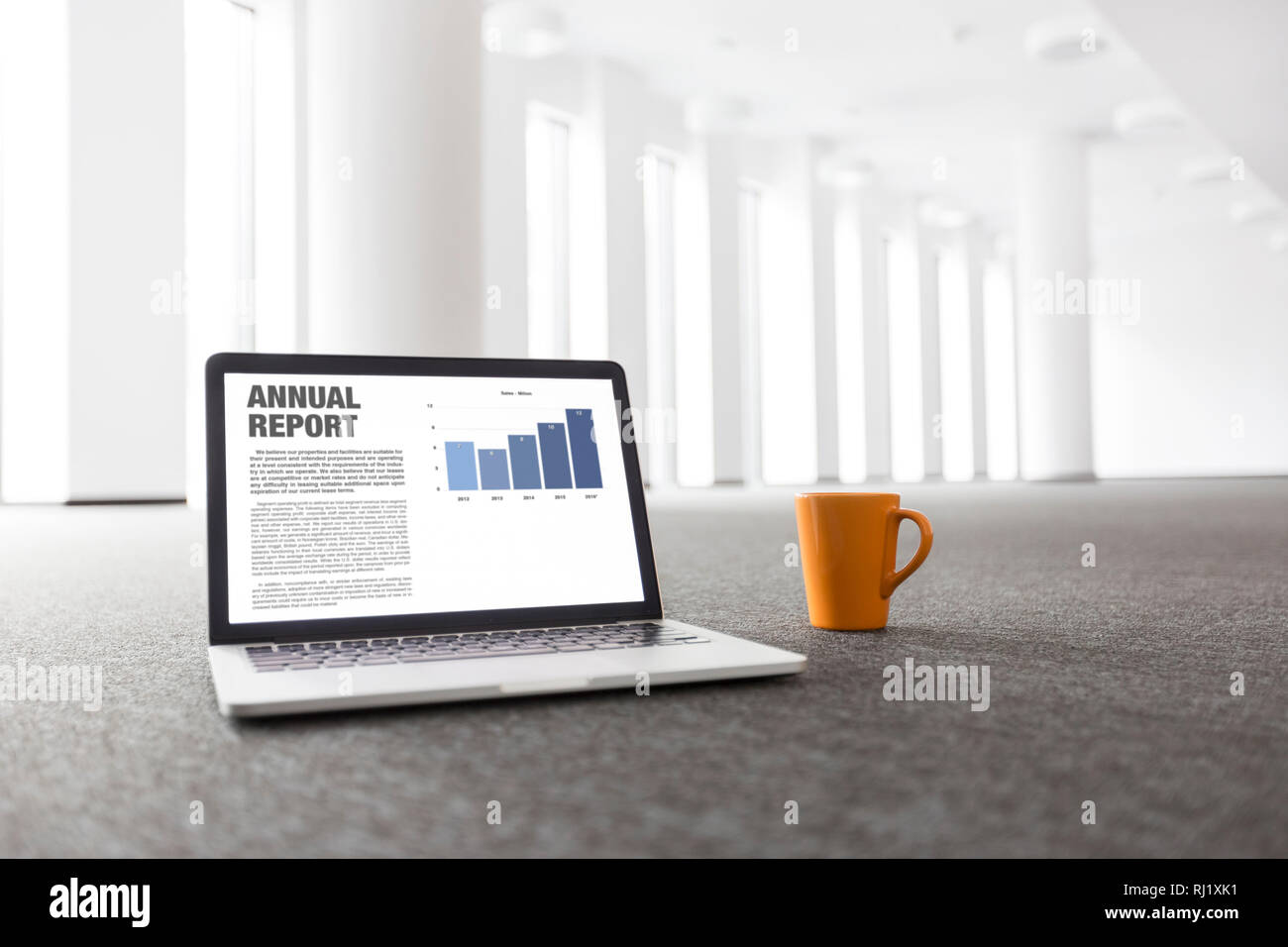 Relazione annuale grafico su computer portatile dalla tazza da caffè al nuovo ufficio vuoto Foto Stock