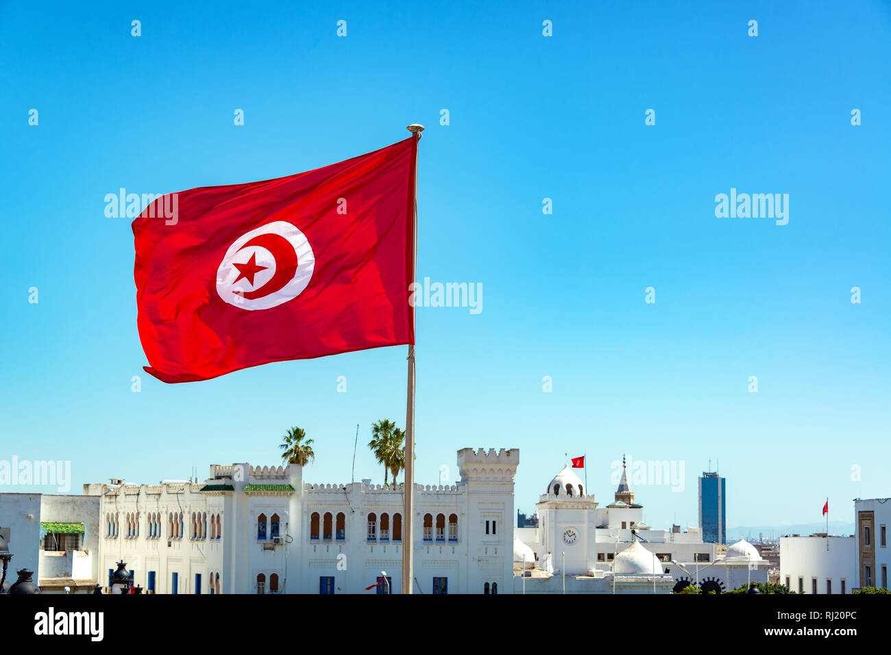 Bandiera della Tunisia sventolare a Tunisi con edifici governativi in background Foto Stock