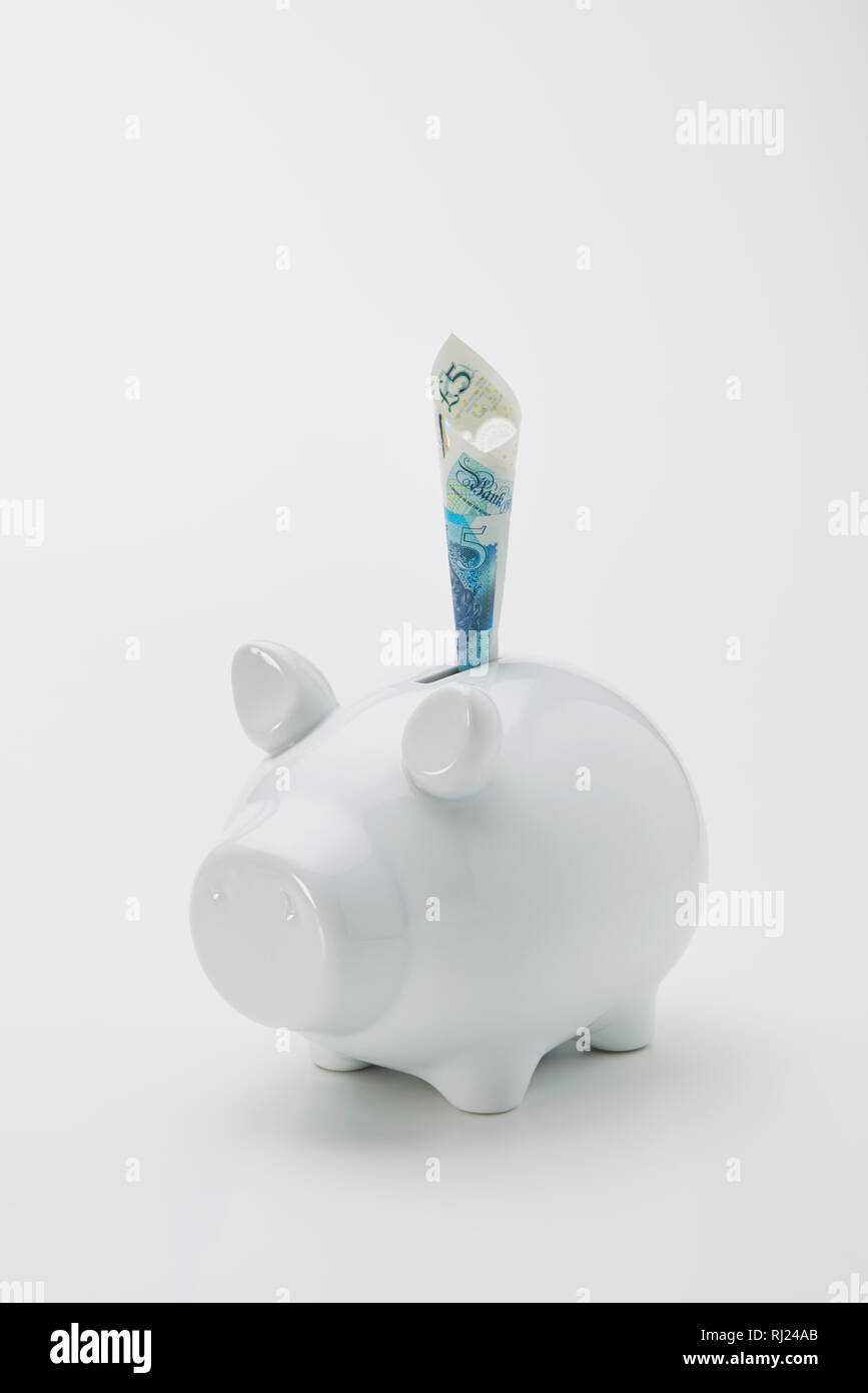 Contemporaneo di colore bianco Salvadanaio con cinque Pound nota Foto Stock