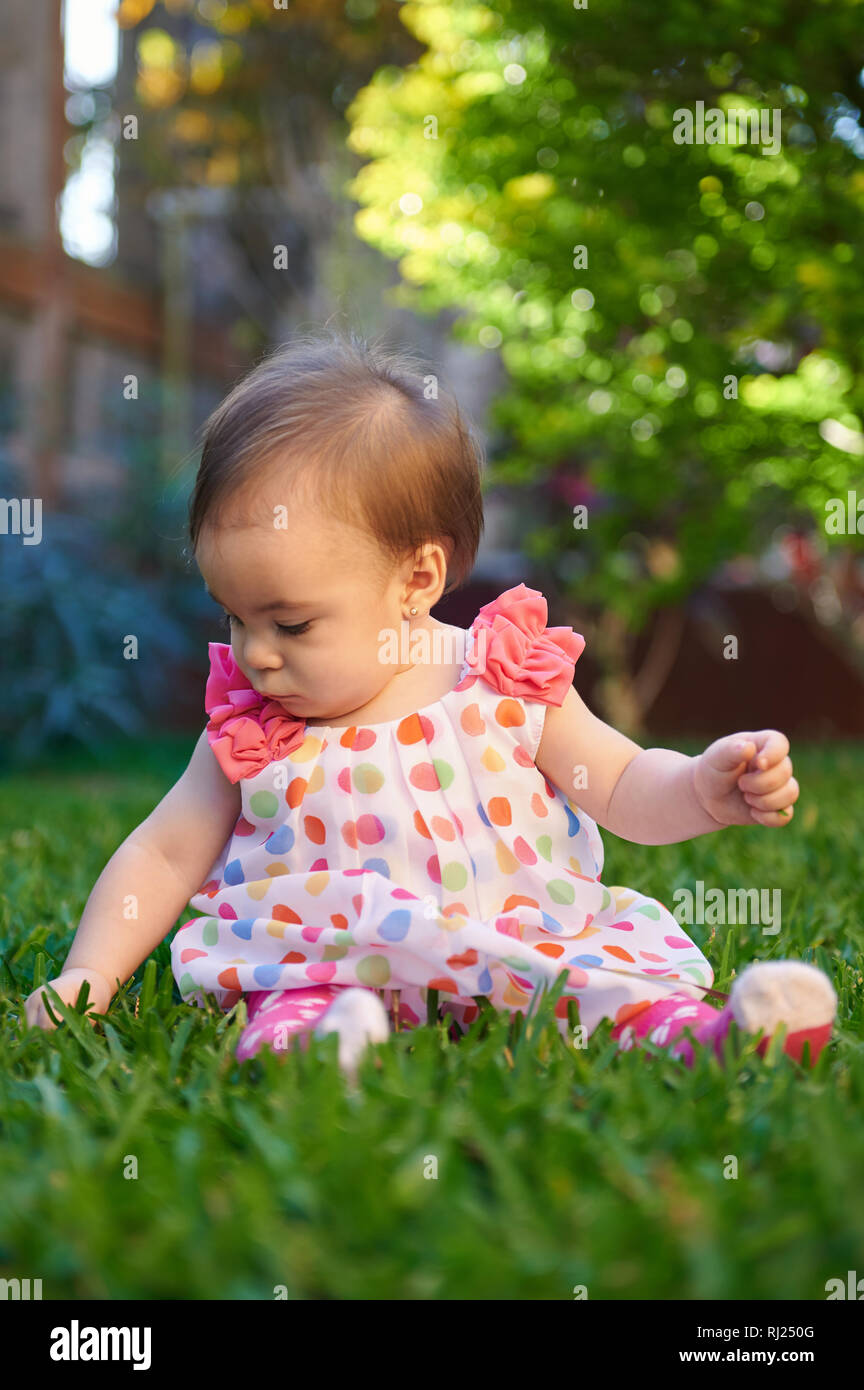Baby girl giocare su erba parco nella soleggiata estate sfondo Foto Stock