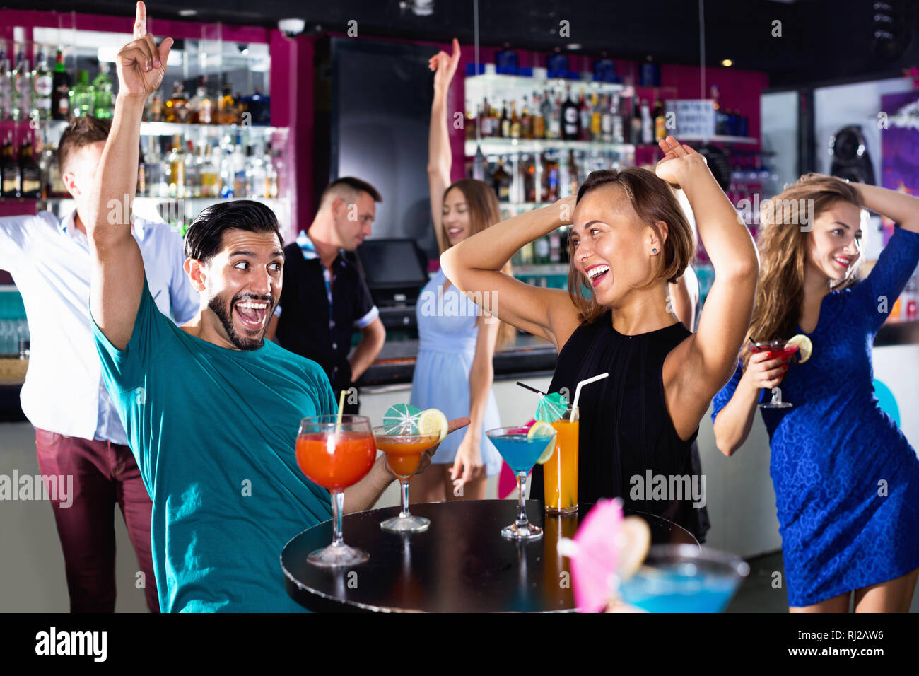 Felice allegro uomo positivo con giovani donne stanno godendo il partito in bar. Foto Stock