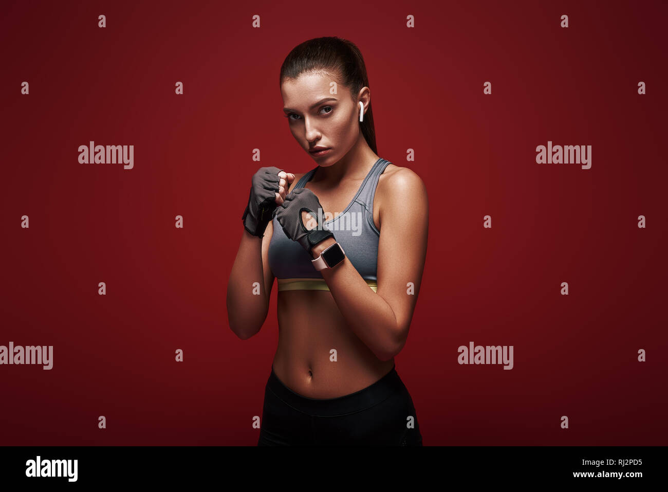 Bella sportive indossando guanti di allenamento è pronto per l'esercizio. Isolato su sfondo rosso Foto Stock