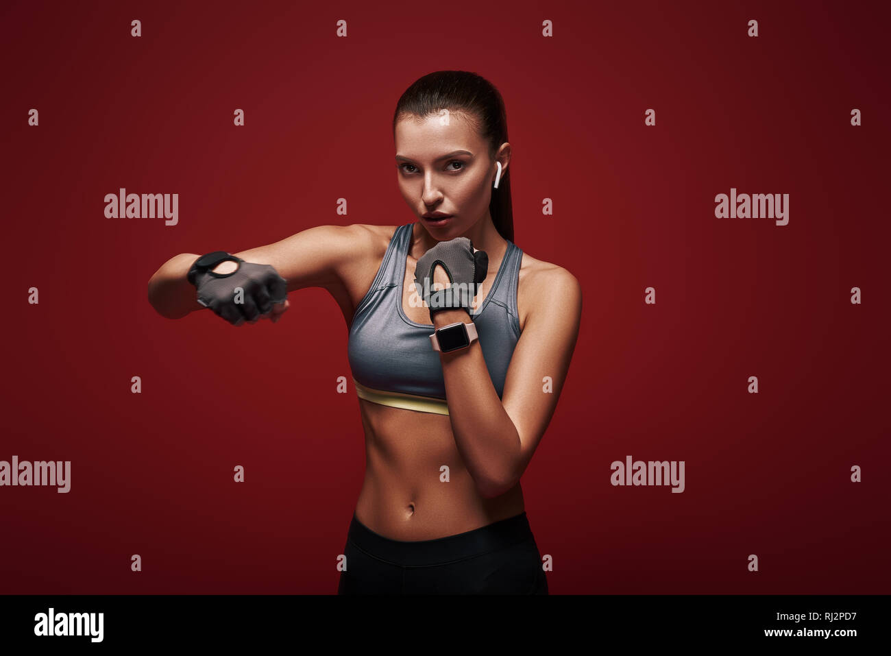 Giovani belle sportive indossando guanti di allenamento è pronta per la lotta contro un avversario. Isolato su sfondo rosso Foto Stock