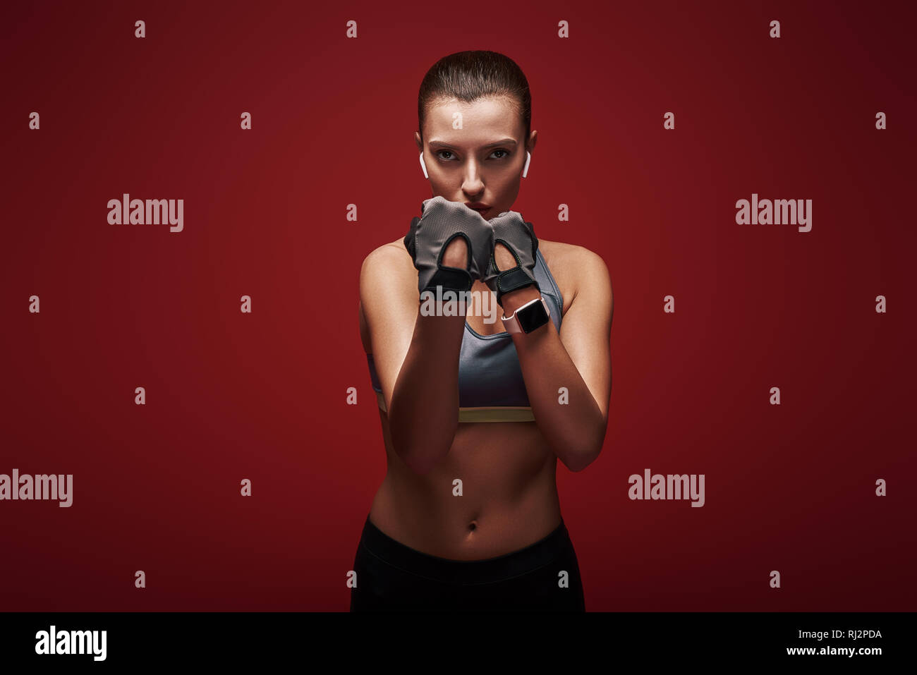 Giovani belle sportive indossando guanti di allenamento è pronta per la lotta contro un avversario. Isolato su sfondo rosso Foto Stock