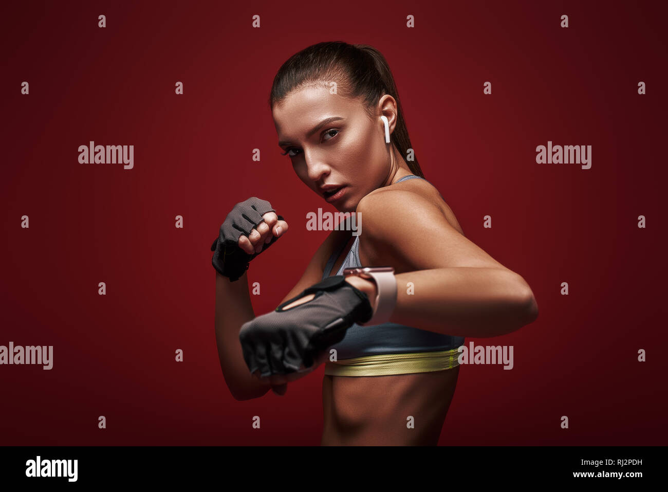 Ritratto di giovane bella sportive indossando guanti di allenamento. Ella è pronta per la lotta contro un avversario. Isolato su sfondo rosso Foto Stock