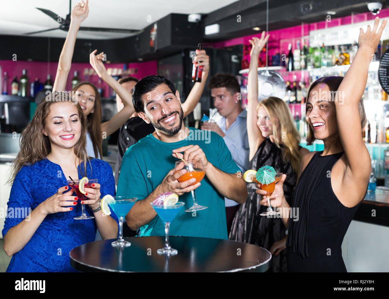 Uomo sorridente con due donne stanno bevendo un cocktail sulla parte aziendale Foto Stock