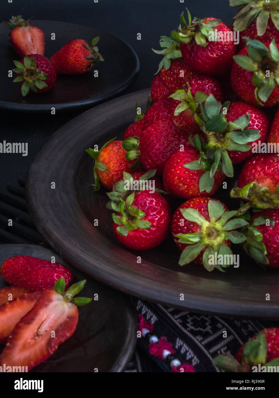 Pila di fresche Fragole rosso sulla piastra nera - Fotografia scuro Foto Stock