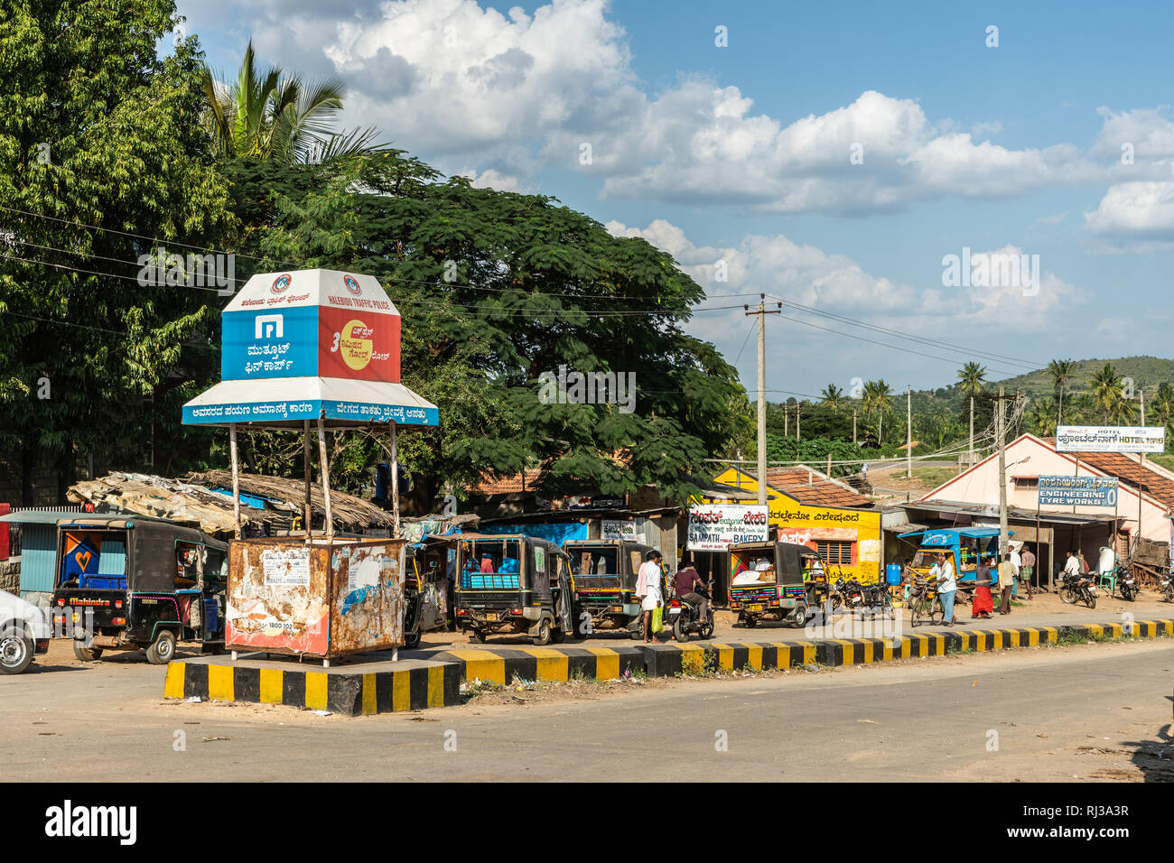 Halebidu, Karnataka, India - 2 Novembre 2013: vista sulla strada della città vicino al tempio Hoysalaswara, con piccolo traffico di auto, biciclette e persone. Cintura verde Foto Stock